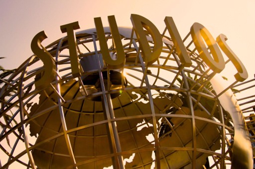 The iconic Universal Studios globe sculpture illuminated by golden sunlight at the entrance to the famous Hollywood theme park and film studio.