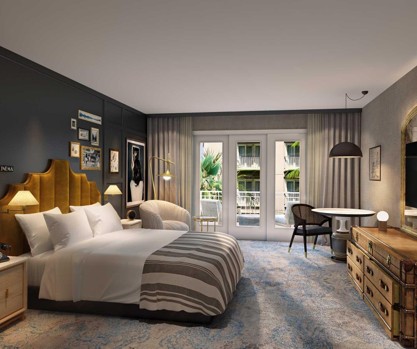 Modern hotel bedroom with a mustard headboard, gallery wall, and balcony doors overlooking a palm-lined pool.