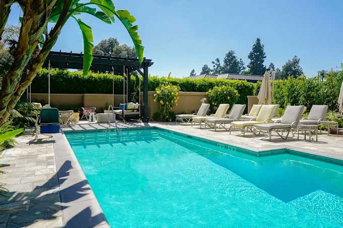 Hotel Amarano Burbank outdoor pool surrounded by palm trees and lounge chairs.